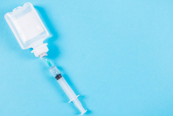 syringe inserted normal saline solution plastic bottle blue background - 写真・画像
