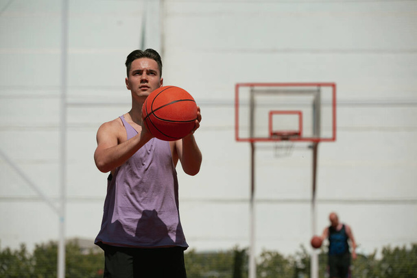 Genç adam basketbol sahasında basketbol oynuyor. Topu ringe fırlattı. Spor yapıyorum. sağlıklı vücut ve sağlıklı yaşam tarzı - Fotoğraf, Görsel