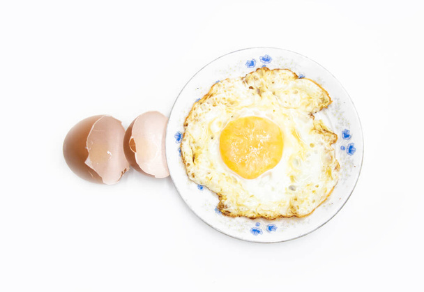 ovo frito em uma placa com a pele de ovo quebrada isolada no fundo branco na visão superior. Culinária alimentar - Foto, Imagem