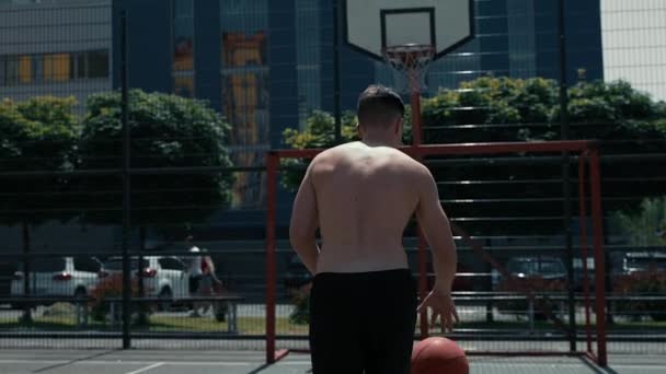 mladík hraje basketbal na basketbalovém hřišti. hodí míč do ringu. sportuje. zdravé tělo a zdravý životní styl - Záběry, video