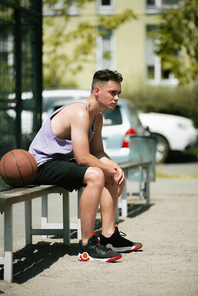 young guy plays basketball on the basketball court. throws the ball into the ring. doing sports. healthy body and healthy lifestyle - Foto, imagen