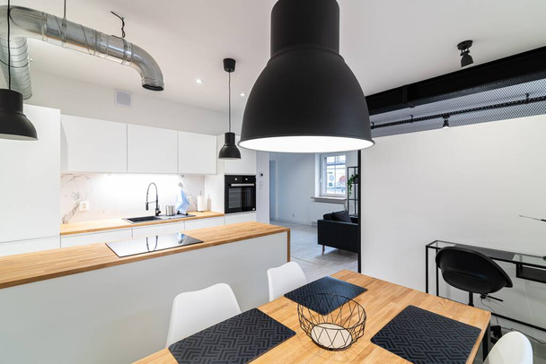 Moderni keittiö, jossa on ruokailutila ja tiski. Valkoinen ja puukalusteet - Valokuva, kuva