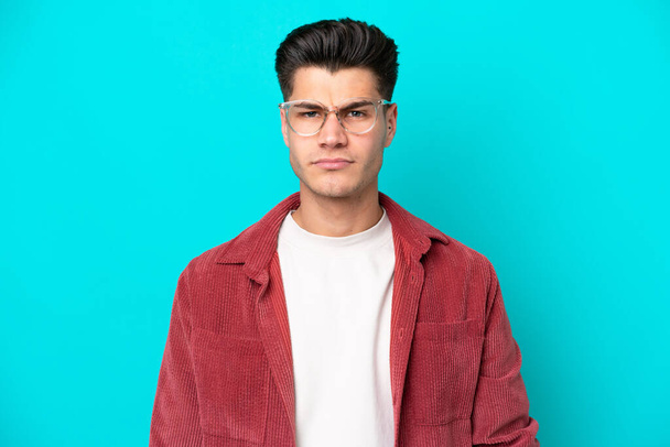 Young handsome caucasian man isolated on blue bakcground With glasses - Foto, Imagem