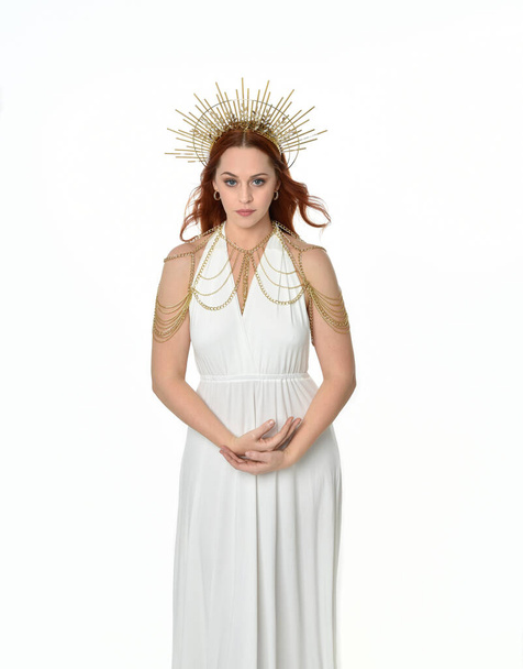 portrait of beautiful red head woman wearing long flowing fantasy toga gown with angelic  golden halo crown on studio background - Fotoğraf, Görsel