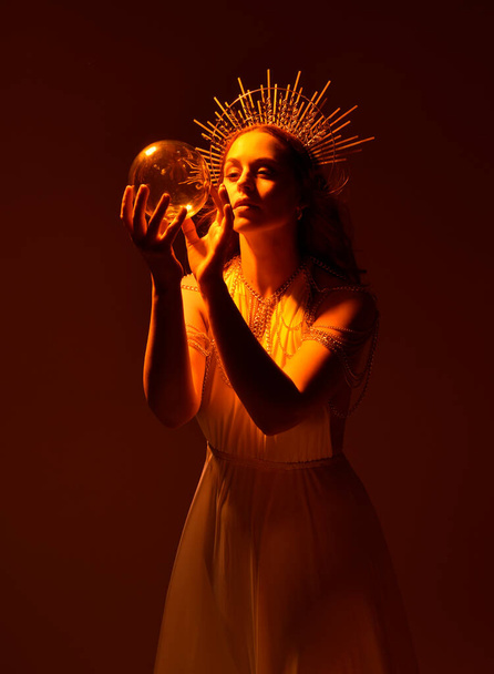 retrato de bela mulher cabeça vermelha vestindo vestido de toga fantasia fluindo longo com coroa halo dourado angelical no fundo do estúdio - Foto, Imagem