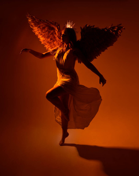 portré gyönyörű vörös hajú nő visel hosszú folyású fantasy tóga köntös angyali arany glória korona stúdió háttér - Fotó, kép