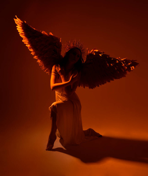portrait de belle femme de tête rouge portant longue robe de toge fantaisie fluide avec couronne halo d'or angélique sur fond de studio - Photo, image