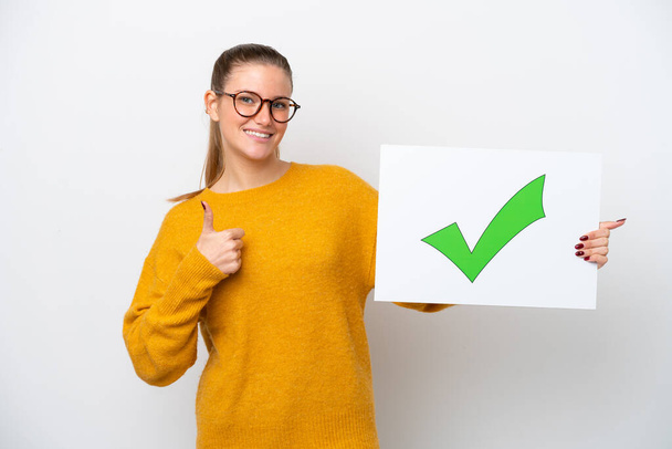 Young caucasian woman isolated on white background holding a placard with text Green check mark icon with thumb up - Photo, Image
