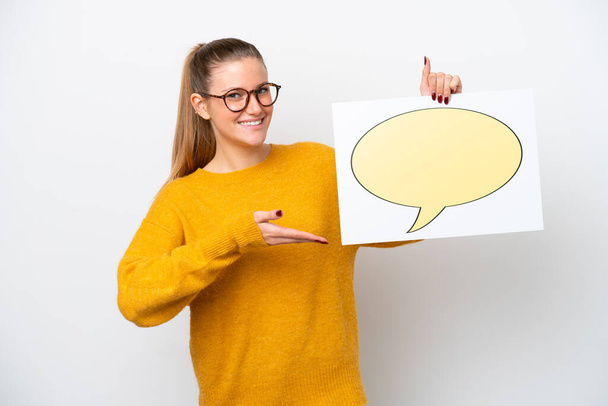 Young caucasian woman isolated on white background holding a placard with speech bubble icon and pointing it - Photo, Image