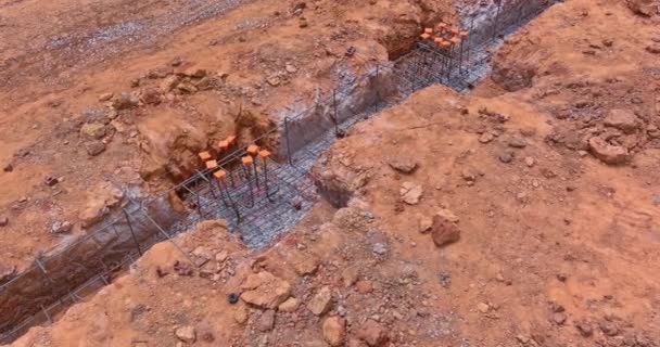 Een bouwplaats wordt voorbereid met gegraven greppel onder een betonnen fundering voor een nieuw huis een luchtfoto - Video
