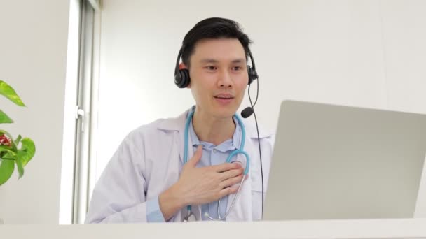 Azjatycki lekarz uśmiecha się pięknie Świadcząc usługi lecznicze dla pacjentów z rozmów online przez Internet na laptopach. koncepcja lekarza online.  - Materiał filmowy, wideo