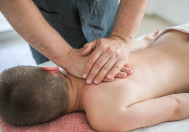 Boy toddler relaxes from a therapeutic massage. Physiotherapist working with patient in clinic to treat the back of a child - Fotoğraf, Görsel