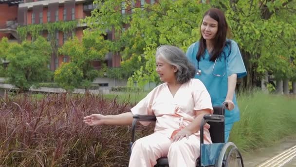 Hastanelerde tıbbi hizmet kavramı. Hasta bakımı. Kadın doktor ameliyat önlüğü giyiyor ve tekerlekli sandalyede oturan yaşlı bir hastayı tedavi ediyor.. - Video, Çekim