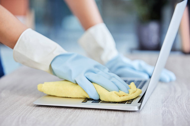 Nierozpoznawalna kobieta czyszcząca laptopa w swoim mieszkaniu. Jedna nieznana kobieta użyła szmaty do usunięcia kurzu z klawiatury laptopa. - Zdjęcie, obraz