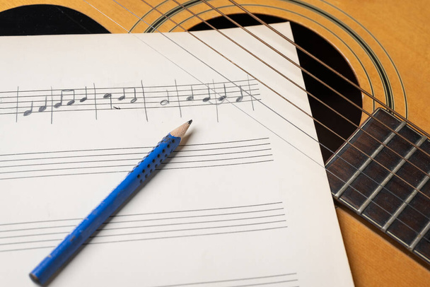 Music recording scene with guitar, music sheet and pencil on wooden table - Фото, зображення