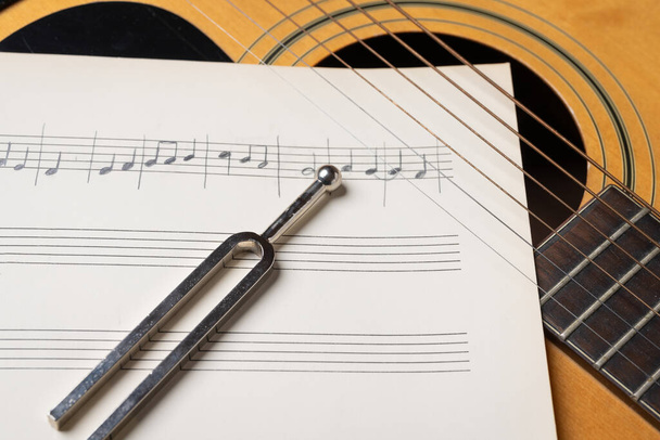 Music recording scene with guitar, music sheets and tuning fork on wooden table, closeup - Photo, image