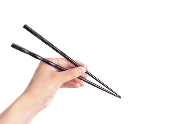Black lacquered chopsticks in hand isolated on white background with copy space. - Valokuva, kuva