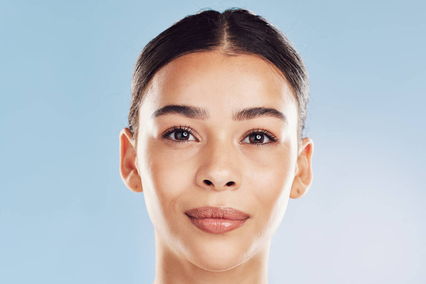 Closeup face beautiful young mixed race woman. An attractive female posing in studio isolated against a blue background. A skincare regime that keeps your skin soft, smooth, glowing and healthy. - Фото, зображення