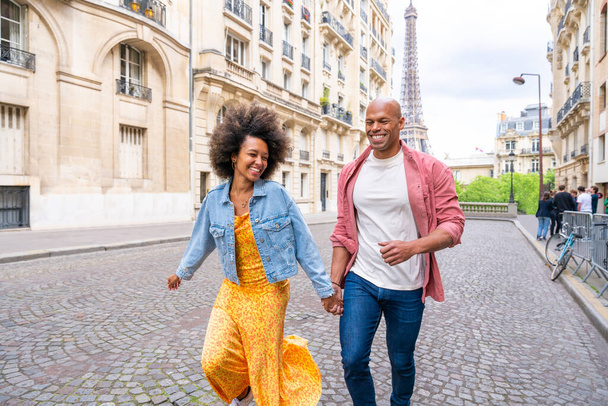 Black cheerful happy couple in love visiting Paris city centre and Eiffel Tower - African american tourists travelling in Europe and dating outdoors - Фото, изображение
