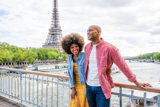 Black cheerful happy couple in love visiting Paris city centre and Eiffel Tower - African american tourists travelling in Europe and dating outdoors - Фото, изображение