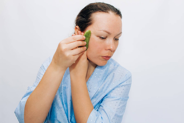 The girl makes a massage with a jade massager close-up, problem skin. - Foto, imagen