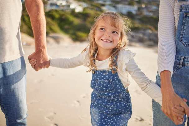Rozkošná holčička se usmívá při procházce po pláži s prarodiči a drží se za ruce. Roztomilý kavkazský dívka těší rodinný čas na pláži. - Fotografie, Obrázek