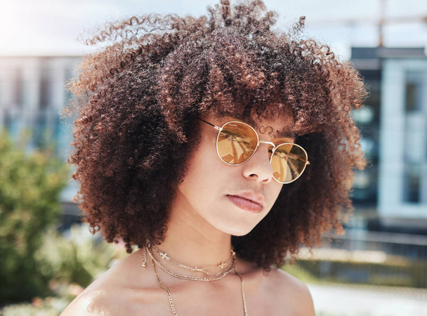 πρόσωπο μιας όμορφης νεαρής Αφροαμερικανής γυναίκας με ένα σγουρό αφρό που φοράει γυαλιά ηλίου έξω. Δροσερό, μοντέρνο, hipster γυναίκα φορώντας κίτρινα γυαλιά ηλίου απολαμβάνοντας την ημέρα έξω το καλοκαίρι. Κομψή γυναίκα.. - Φωτογραφία, εικόνα