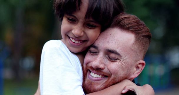 Dad and son embrace huggging each other outside, white father and mixed race child - Photo, Image