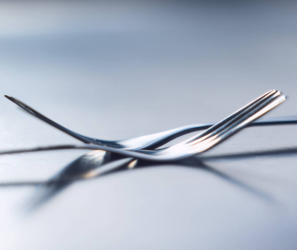 Two forks side by side symbolizing togetherness, dependency and unity. A symbol of teamwork, relationship and partnership issues and troubles, or dependencies between countries or companies. - Foto, Imagem