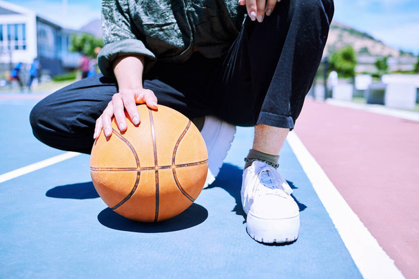 Невпізнана людина готується насолоджуватися грою в баскетбол на дворі зовні. Невпізнаваний баскетболіст стоїть на дворі з м'ячем, який готується грати
. - Фото, зображення