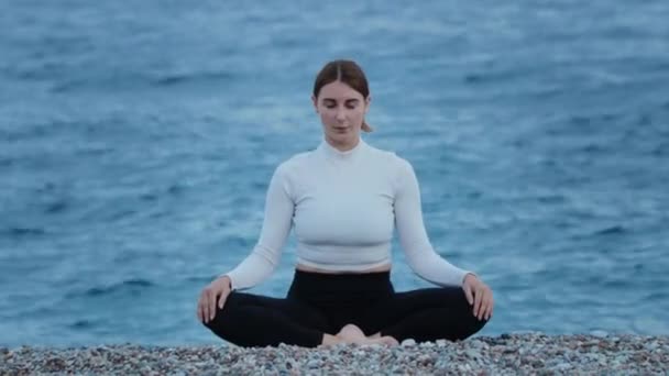 Deportes al aire libre: una mujer que hace yoga y ejercicios de respiración junto al mar azul. Mid shot - Metraje, vídeo