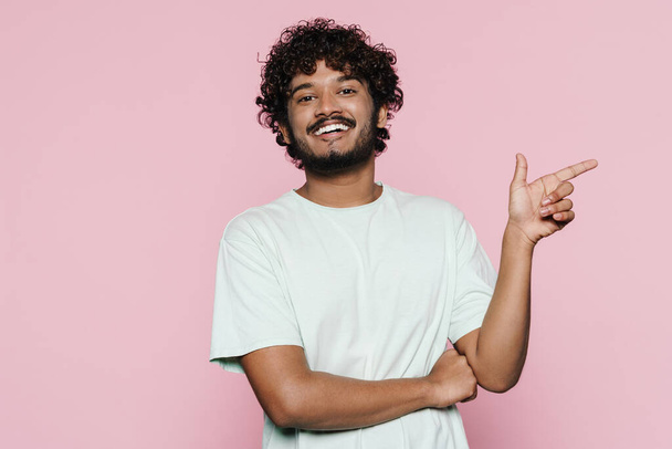 Young middle eastern man smiling and pointing finger aside isolated over pink wall - Zdjęcie, obraz