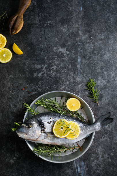 Сырая рыба с пряностями. Дорадо и ингредиенты для приготовления пищи на столе - Фото, изображение