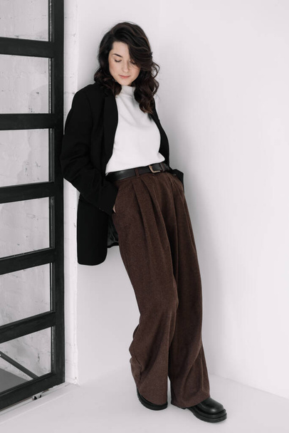 Fashion portrait of a woman with a model look without emotions. Stylish image of a young businesswoman, director or manager, creative woman dressed in stylish office clothes, pants and jacket - Fotó, kép