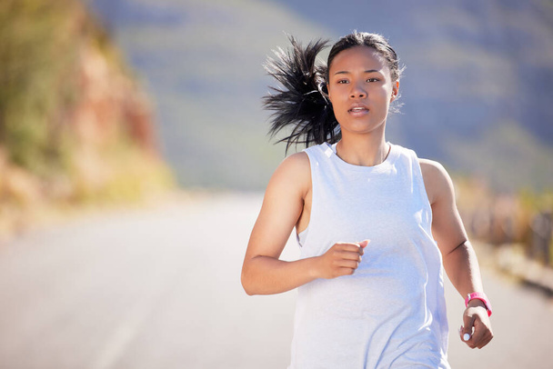 Active mixed race young woman running for exercise outdoors. Athlete jogging for a refreshing cardio training workout in the morning. Determined to build endurance to reach fitness and wellness goals. - Photo, Image