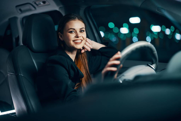 foto horizontal de uma mulher bonito, relaxado sentado ao volante de um carro sorrindo agradavelmente em um estado descontraído. Foto sobre o tema da condução segura. Foto de alta qualidade - Foto, Imagem
