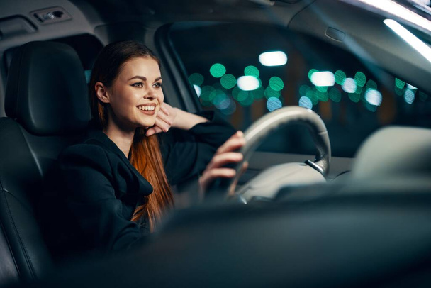een vrolijke, vrolijke vrouw zit achter het stuur van een auto met een veiligheidsgordel om en glimlacht vrolijk naar de weg. Hoge kwaliteit foto - Foto, afbeelding