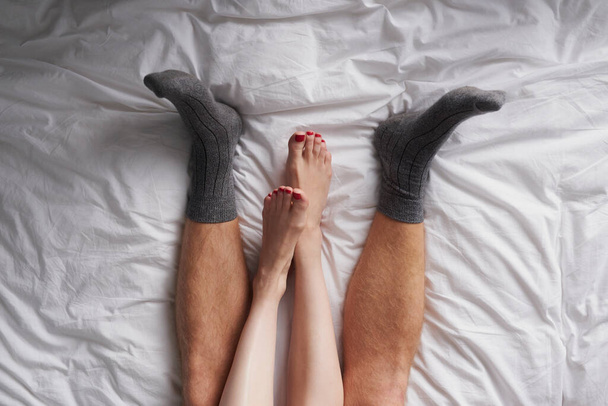 Zbliżenie nóg pary leżącej w łóżku pieszczotliwie przytulającej. - Zdjęcie, obraz