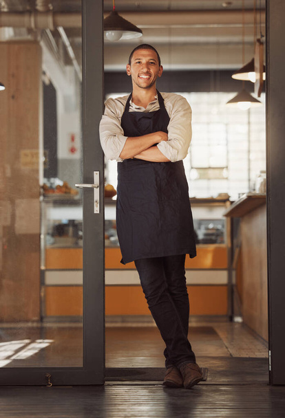 Portrait of proud small business owner in his restaurant. Young mixed race businessman standing in his cafe entrance. Bistro owner arms crossed standing in his supermarket. Boss standing by his door. - Photo, Image