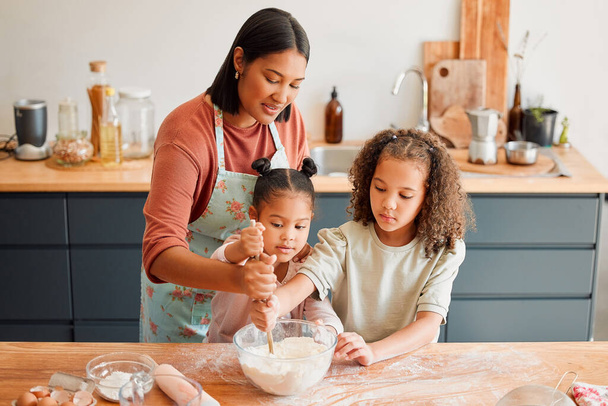 Females only, happy mixed race family of three cooking in a messy kitchen together. Loving black single parent bonding with her daughters while teaching them domestic skills at home. - Foto, imagen