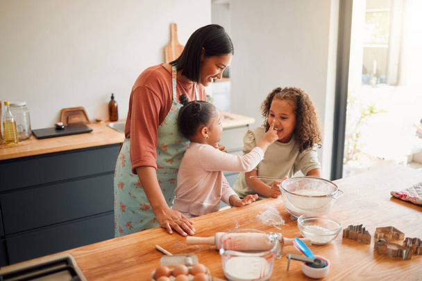 Females only, happy mixed race family of three cooking in a messy kitchen together. Loving black single parent bonding with her daughters while teaching them domestic skills at home. - Foto, immagini