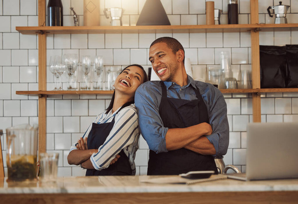 Cheerful businesspeople standing in their cafe kitchen. Business partners standing back to back in their coffeeshop. Two entrepreneurs arms crossed in their restaurant kitchen - Fotó, kép