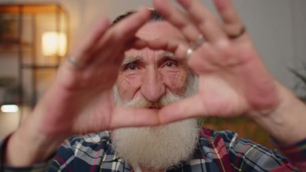 I love you. Senior grandfather makes symbol of love, showing heart sign to camera, express romantic feelings, express sincere positive feelings. Charity, gratitude, donation. Man close-up happy face - Metraje, vídeo
