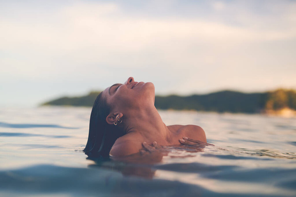 Sexy young woman swimming in the sea. Enjoying a summer vacation and relaxing weekend. - Foto, Bild