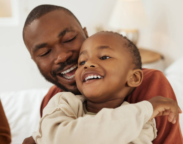 Iloinen pieni afrikkalainen amerikkalainen poika, joka pitää hauskaa kiintyessään isäänsä kotona. Nuori isä ja hänen pieni poikansa jakavat herkän hetken. - Valokuva, kuva