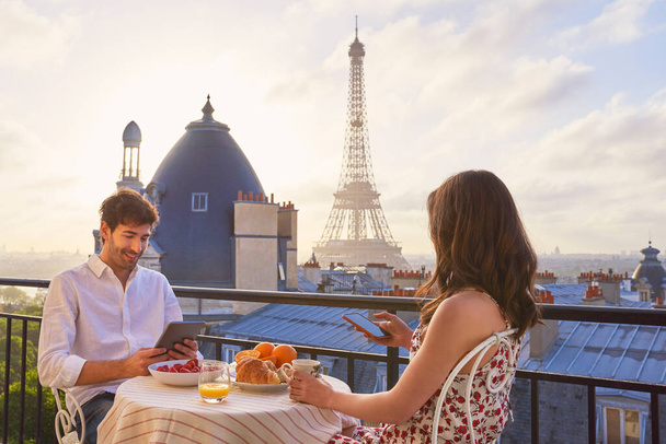 Foto de una joven pareja desayunando en el balcón de un apartamento con vistas a la Torre Eiffel en París, Francia. - Foto, Imagen