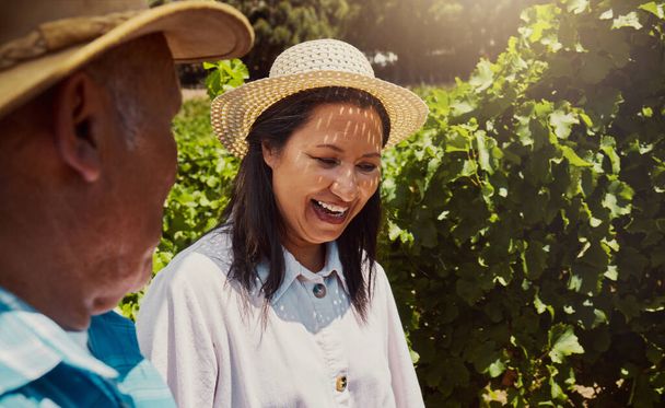 Glimlachend gemengd ras koppel hechting op wijngaard. Gelukkige Spaanse man en vrouw lachend en genietend van de dag op een boerderij na wijnproeverij tijdens een weekend. Man en vrouw dragen hoeden en staan samen - Foto, afbeelding