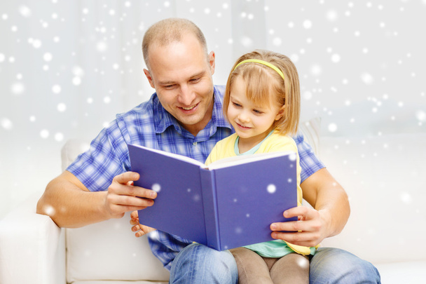 smiling father and daughter with book at home - Valokuva, kuva