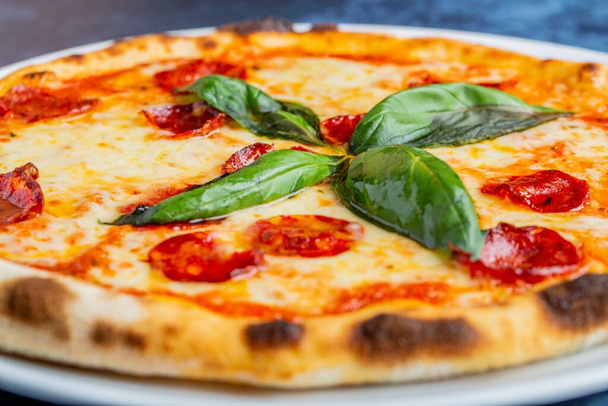 Pizza de pepperoni saborosa fresca com folhas de manjericão na mesa - Foto, Imagem
