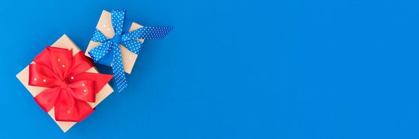 Weihnachts- oder Geburtstagsgeschenkschachteln mit roter und blauer Schleife über blauem Hintergrund mit Kopierraum. Festlicher Hintergrund mit Kopierplatz für Ihr Projekt oder Ihre Grußkarte. Banner - Foto, Bild